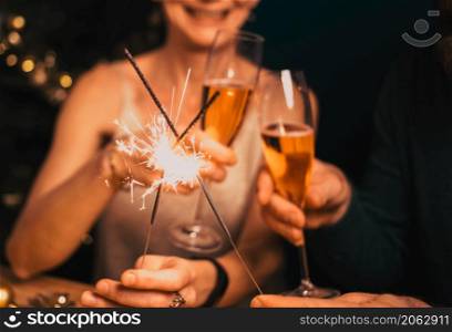 happy couple holding sparkles and champagne glasses New Year party