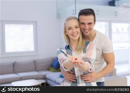 Happy couple hugging and showing small red house in hands Concept of buying house to start a family