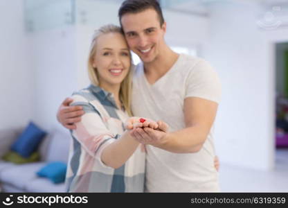 Happy couple hugging and showing small red house in hands Concept of buying house to start a family