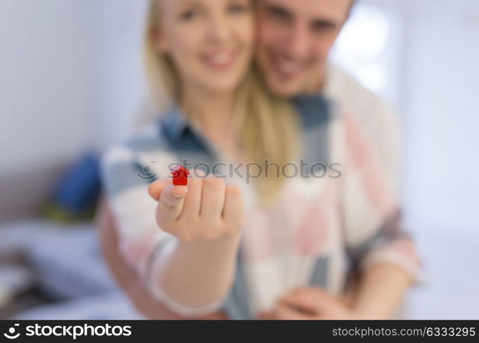 Happy couple hugging and showing small red house in hands Concept of buying house to start a family