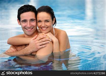 Happy couple hugging in a swimming-pool