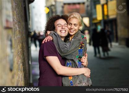 Happy couple hugging in urban background on a typical London street. UK.. Young couple hugging in urban background on a typical London street.