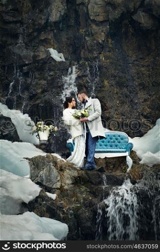 Happy couple hugging on rock on the background of nature. Fashion style. Family outdoors. Man and woman. Bride and groom