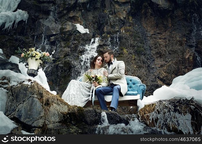 Happy couple hugging on rock on the background of nature. Fashion style. Family outdoors. Man and woman. Bride and groom