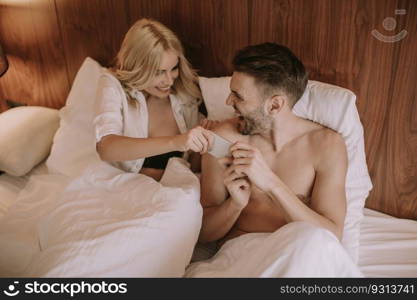 Happy couple in bed at home and use mobile phone