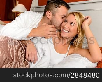 Happy couple in bed man giving kiss woman cheek