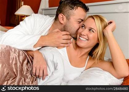 Happy couple in bed man giving kiss woman cheek
