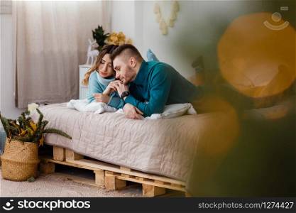 Happy couple in christmas decoration at home. New year eve, decorated fir tree. Winter holiday and love concept.Young happy couple embracing and relaxing on comfortable couch.