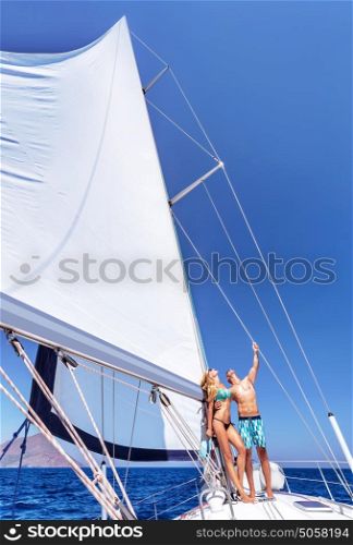 Happy couple in honeymoon vacation in luxury sea cruise, enjoying each other and travel on beautiful sailboat, looking up in the sky