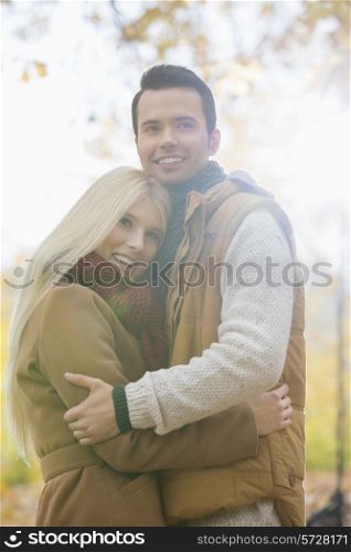 Happy couple in jackets hugging in park