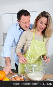 Happy couple in kitchen preparing cake