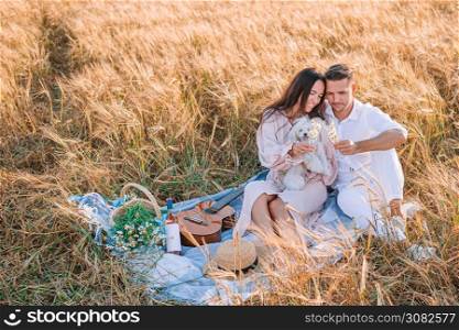 Happy couple in love in the golden field. Young family on picnic in yellow wheat field. Happy young family on picnic in yellow wheat field