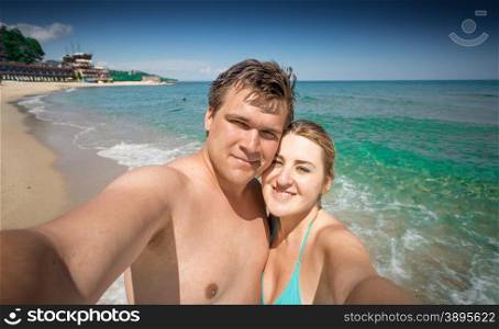 Happy couple in love making selfie on seashore at sunny day