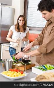Happy couple in modern kitchen with red wine cook together, man cutting pepper