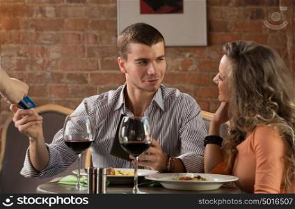 Happy couple in restaurant pay cash free by credit card electronic security money