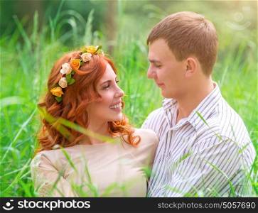 Happy couple in the park, beautiful bride and handsome groom sitting on fresh green grass, love and happiness in wedding day