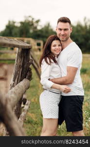 happy couple is hugging near wooden fence. young man and woman are having fun outdoors on a warm summer day. happy couple is hugging near wooden fence. young man and woman are having fun outdoors on a warm summer day.