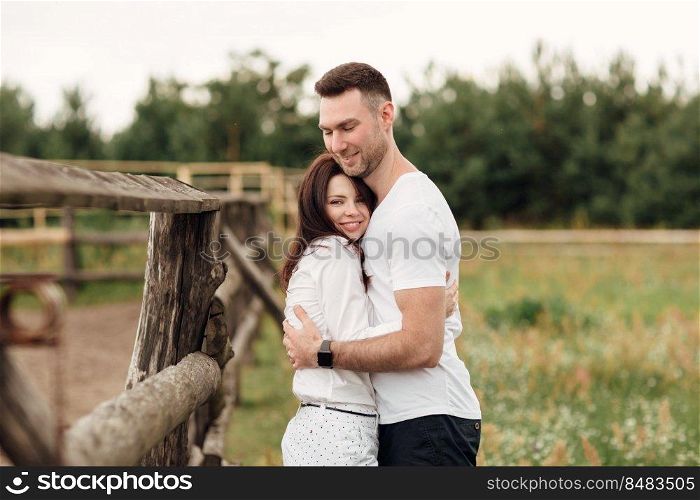 happy couple is hugging near wooden fence. young man and woman are having fun outdoors on a warm summer day. happy couple is hugging near wooden fence. young man and woman are having fun outdoors on a warm summer day.