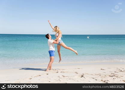 Happy couple jumping on beach vacations. Travel concept of young couple cheering for summer holidays on beach