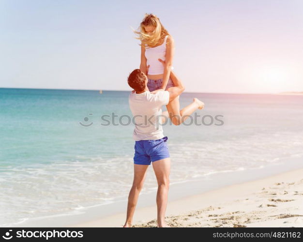 Happy couple jumping on beach vacations. Travel concept of young couple cheering for summer holidays on beach