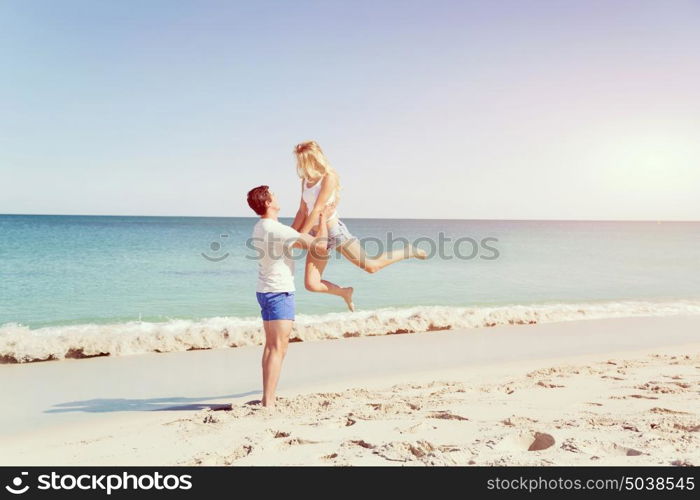 Happy couple jumping on beach vacations. Travel concept of young couple cheering for summer holidays on beach