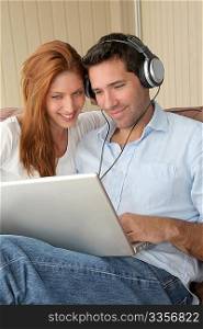 Happy couple listening to music on laptop computer