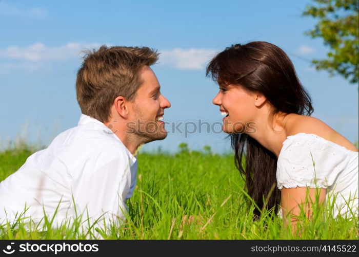 Happy couple lying on a meadow in summer