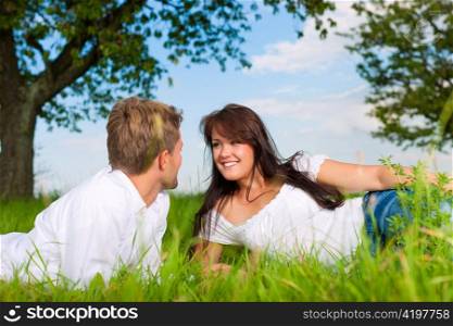 Happy couple lying on a meadow in summer