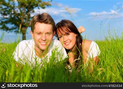 Happy couple lying on a meadow in summer, only feet to be seen