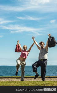 Happy couple man and woman with sport gym bags by sea ocean outdoor. Active young girl and guy in training suit sportswear raising hands up. Happiness.. Happy couple man and woman with sport bags.