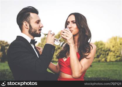 Happy couple of lovers with a glass of wine or champagne standing outdoors.