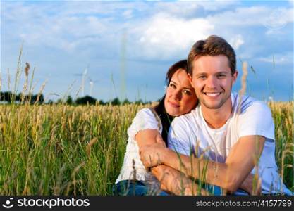 Happy couple on a meadow in summer, man is carrying his woman piggyback