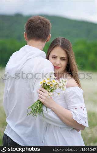 Happy couple on big camomile mountain meadow. Emotional, love and care scene.