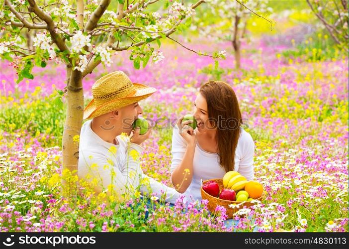 Happy couple on picnic in beautiful blooming garden, eating healthy organic food, romantic date, summer holiday and vacation concept&#xA;