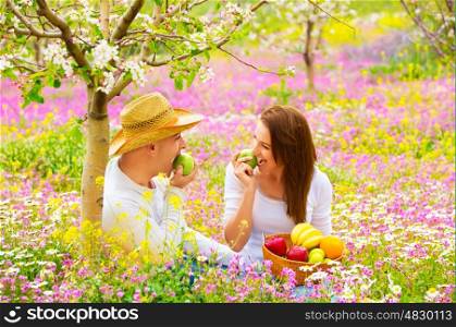Happy couple on picnic in beautiful blooming garden, eating healthy organic food, romantic date, summer holiday and vacation concept&#xA;