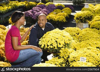 Happy couple picking out fall flowers at outdoor plant market.