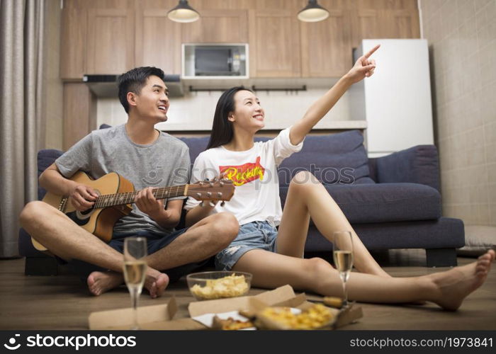 Happy couple playing guitar in the living room