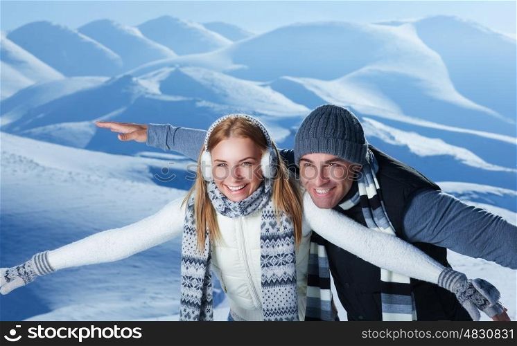 Happy couple playing outdoors in winter, imitate the flight by hands, having fun together in the snowy mountains, with pleasure spending Christmas holidays&#xA;