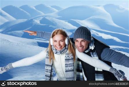 Happy couple playing outdoors in winter, imitate the flight by hands, having fun together in the snowy mountains, with pleasure spending Christmas holidays&#xA;