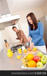Happy couple preparing food together, cutting oranges