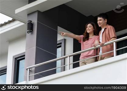 happy couple relaxing and looking from balcony of home