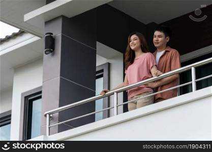 happy couple relaxing and looking from balcony of home