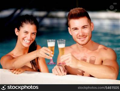 Happy couple relaxing in the pool in the summer celebrating their anniversary with champagne