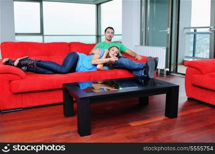 happy couple relaxing on red sofa in big bright new apartment