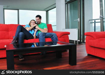 happy couple relaxing on red sofa in big bright new apartment