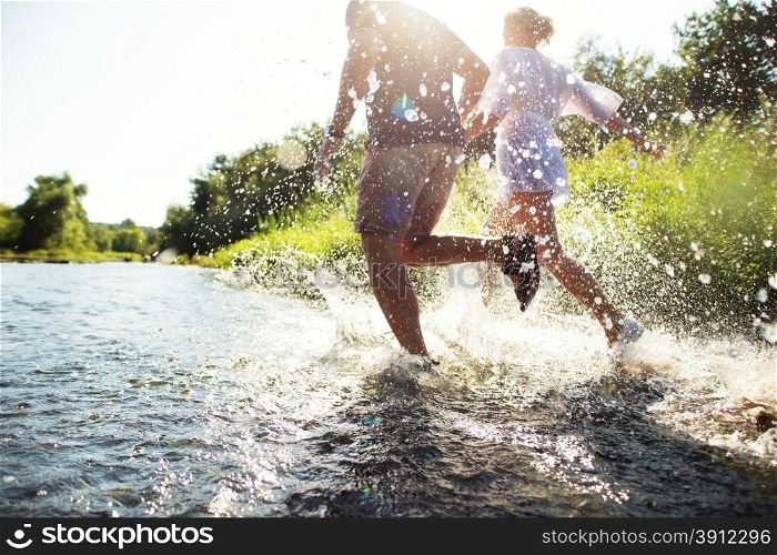 Happy couple running in shallow water. Summertime.