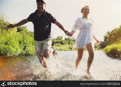 Happy couple running in shallow water. Summertime