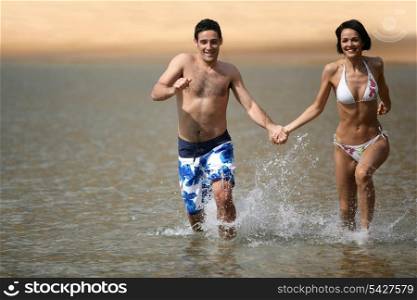 Happy couple running through the sea
