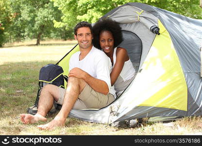 Happy couple sat by entrance to tent