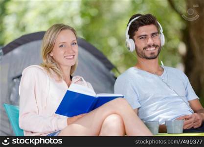 happy couple sitting at the tent reading book